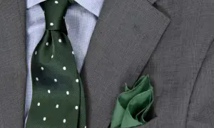 Zielony krawat w kropki do niebieskiej koszuli i szarej marynarki. Elegancka stylizacja.