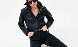 Kobieta w okularach przeciwsłonecznych prezentuje **total black look**: czarną skórzaną kurtkę i jeansy.