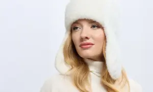 Blondynka w białej, futrzanej czapce uszatce, prezentującej najmodniejsze nakrycia głowy.