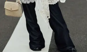 Eleganckie połączenie sukienki ze spodniami. Długie, ciemne dżinsy i biała, koronkowa narzutka tworzą stylowy look.
