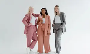 Trzy kobiety prezentują modne spodnie palazzo w stylizacjach: różowej, brzoskwiniowej i szarej.