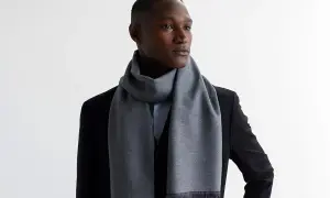 Elegancki mężczyzna w czarnym płaszczu i szarym szaliku. Dowiedz się, jak wiązać szalik do płaszcza damskiego, inspirując się tym stylem.
