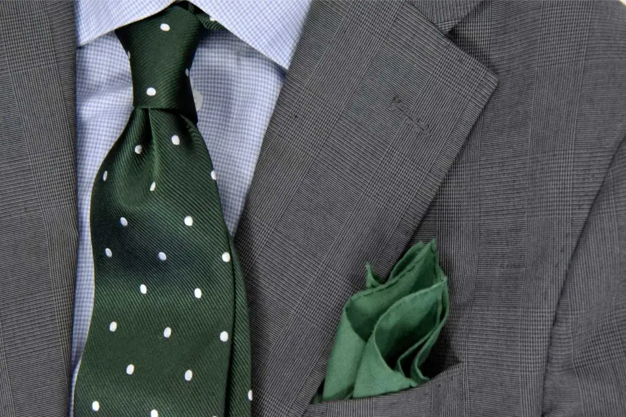 Zielony krawat w kropki do niebieskiej koszuli i szarej marynarki. Elegancka stylizacja.