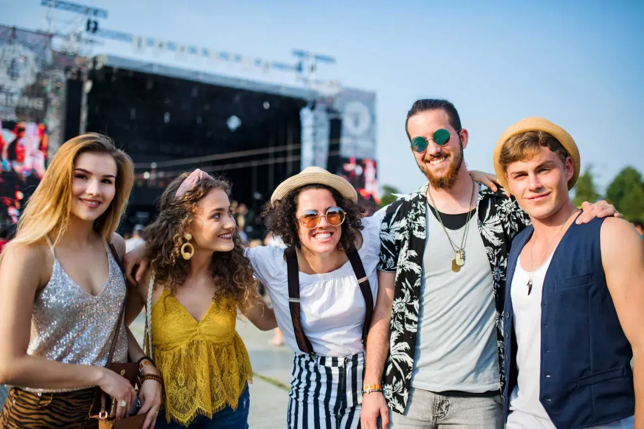 Piątka przyjaciół w letnich stylizacjach na koncert, uśmiechnięci i pełni energii.