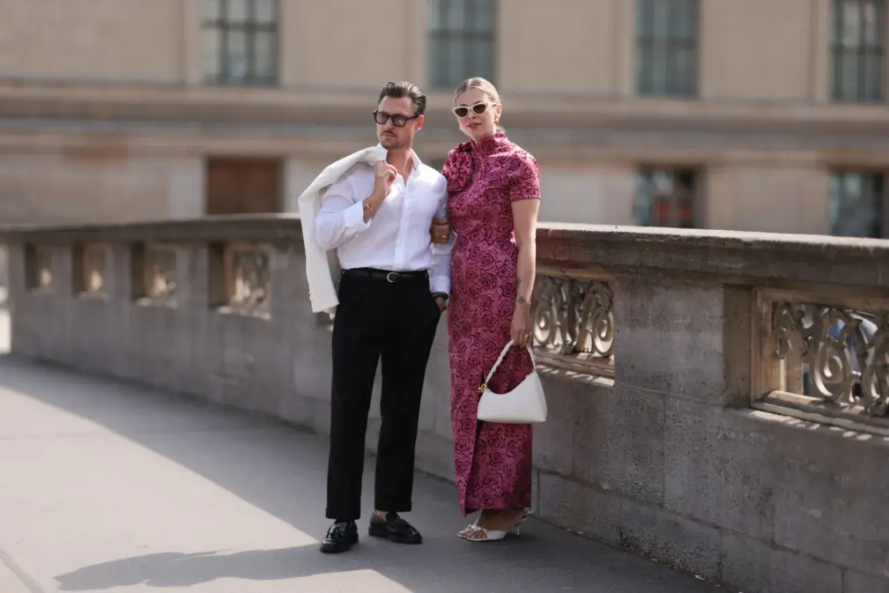 Elegancka para na spacerze, inspiracja, jak się ubrać do teatru. Mężczyzna w białej koszuli i czarnych spodniach, kobieta w różowej sukni.