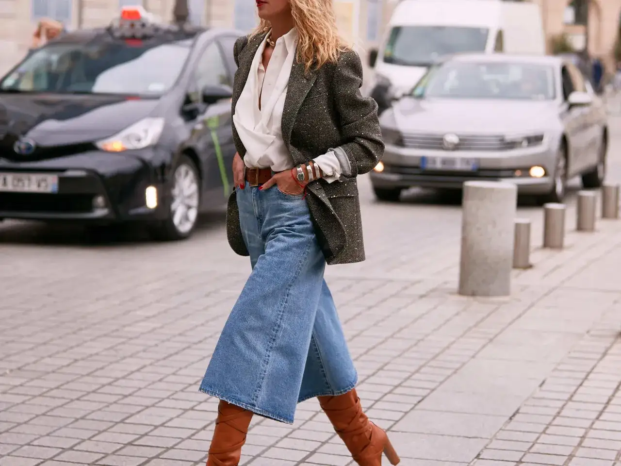 Stylowa kobieta w jeansowych kulotach, białej koszuli i marynarce, prezentuje modne jeansowe kuloty stylizacje.